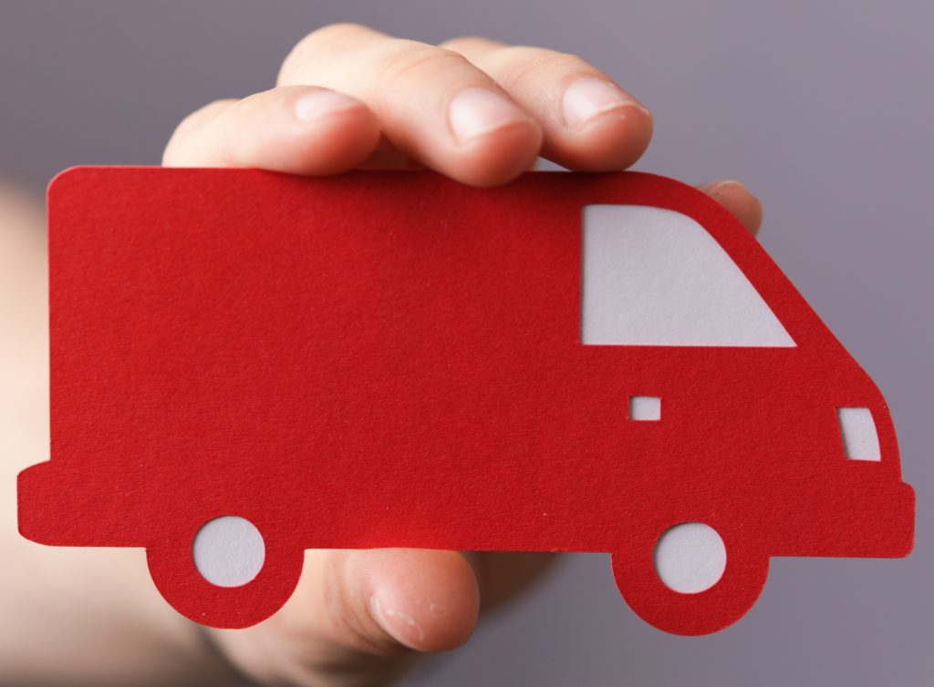 Closeup shot of a man holding a red and white vehicle icon on a grey background